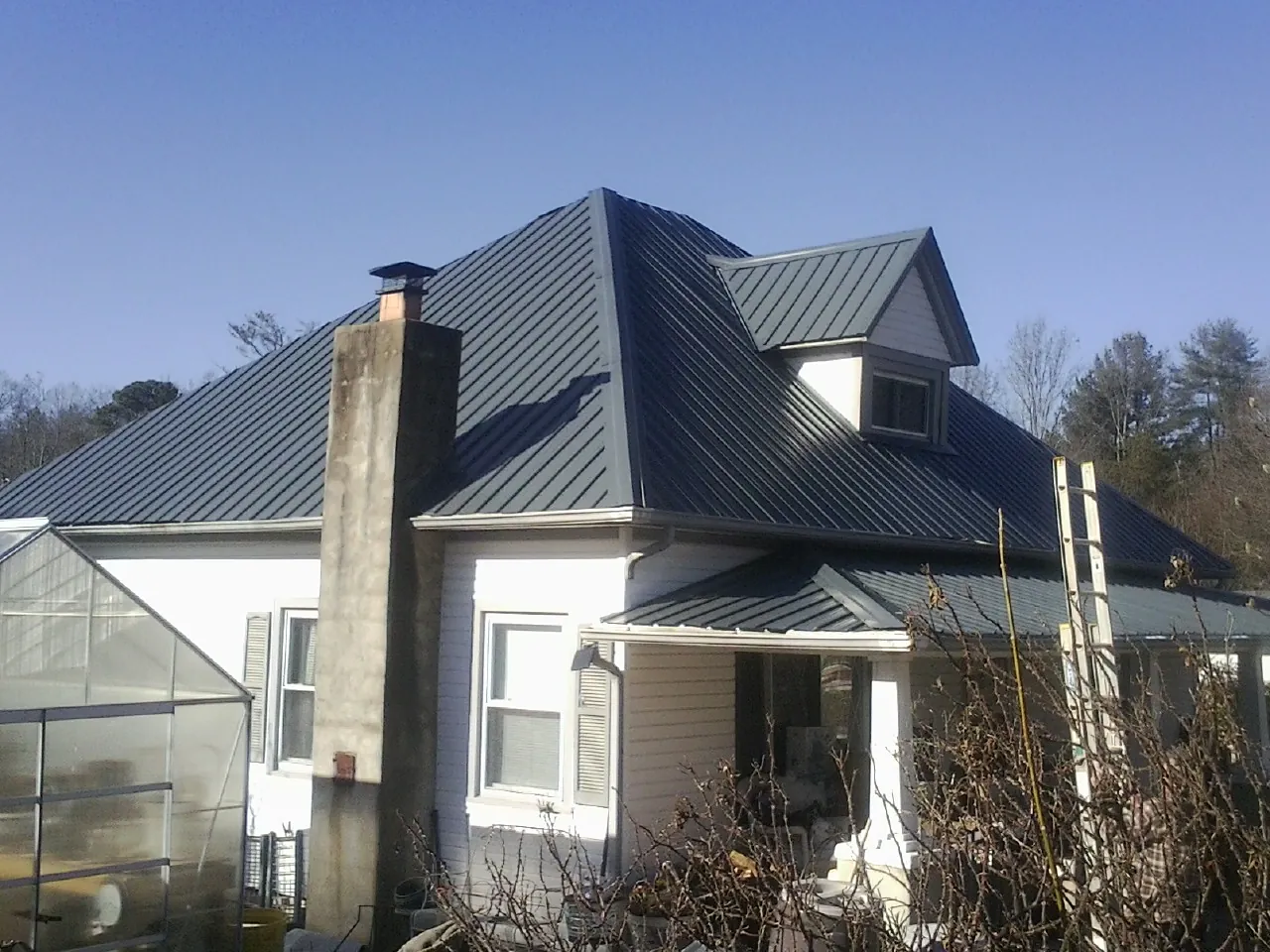 Dark blue standing seam metal roof on a white farmhouse with dormer — Slate & Tile Roof Repair by Roofing Brothers in Pinole
