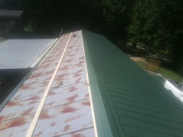 Old rusted panels beside newly installed green metal roofing — Wind Damage Roof Repair by Roofing Brothers in Pinole