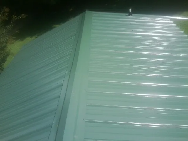 New green metal panels meeting at the ridge of a roof — Flat Roof Repair work by our crew in Pinole