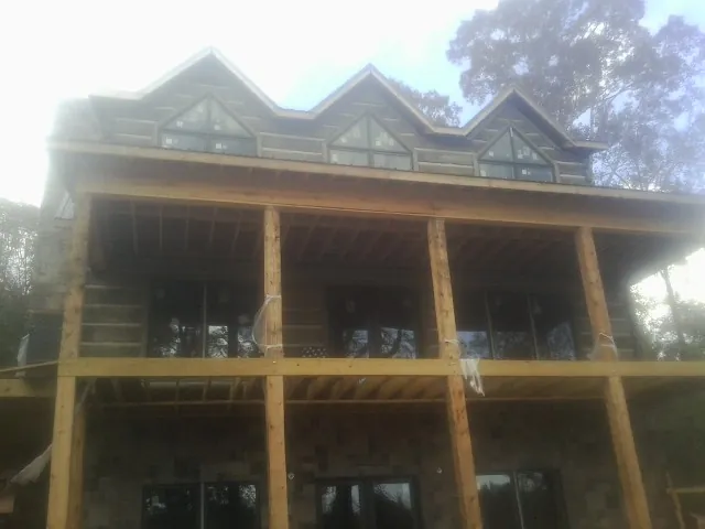 Dormers and porch framing on a large log home under construction — Roof Coating work by our crew in Pinole