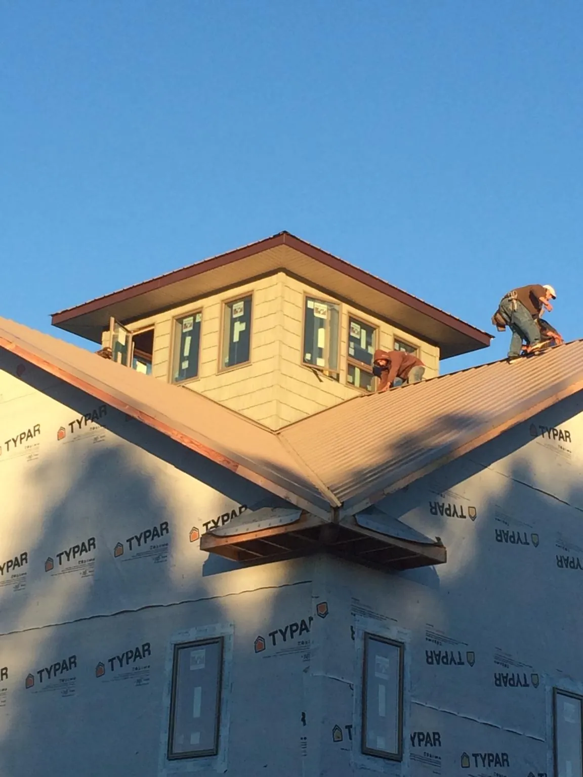 Roofers working around a rooftop cupola on a new metal roof at sunset — Roof Waterproofing in Pinole by Roofing Brothers